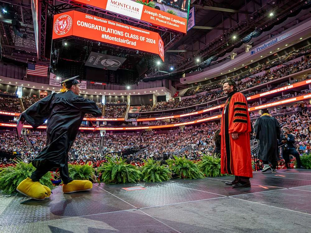 Joseph “Jersey Joe” Lepinski dances across the stage toward President Jonathan Koppell at Montclair’s 2024 Commencement. (Photo by University Photographer Mike Peters)